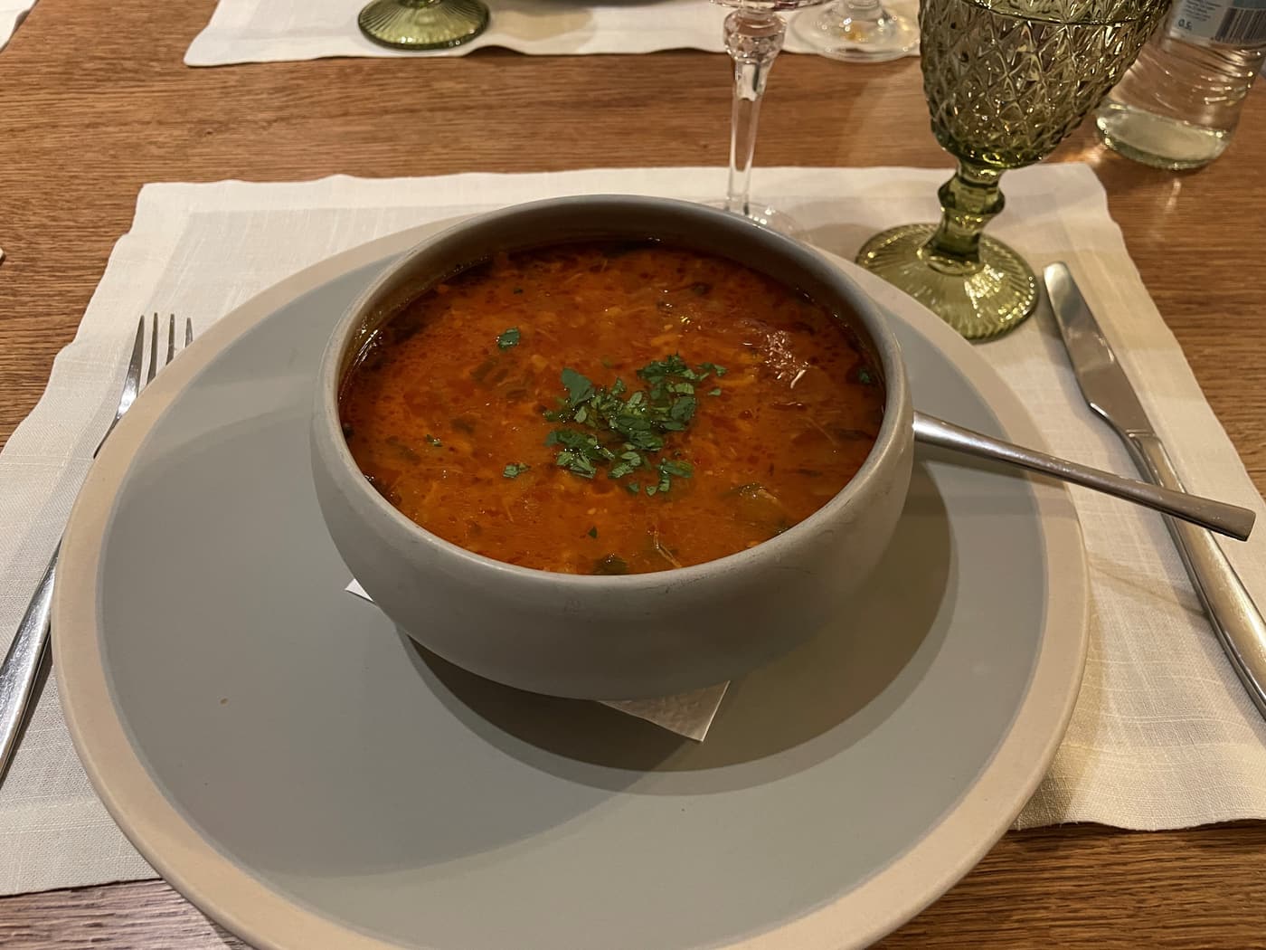 A bowl of spicy Armenian soup topped with fresh herbs at a Riga restaurant