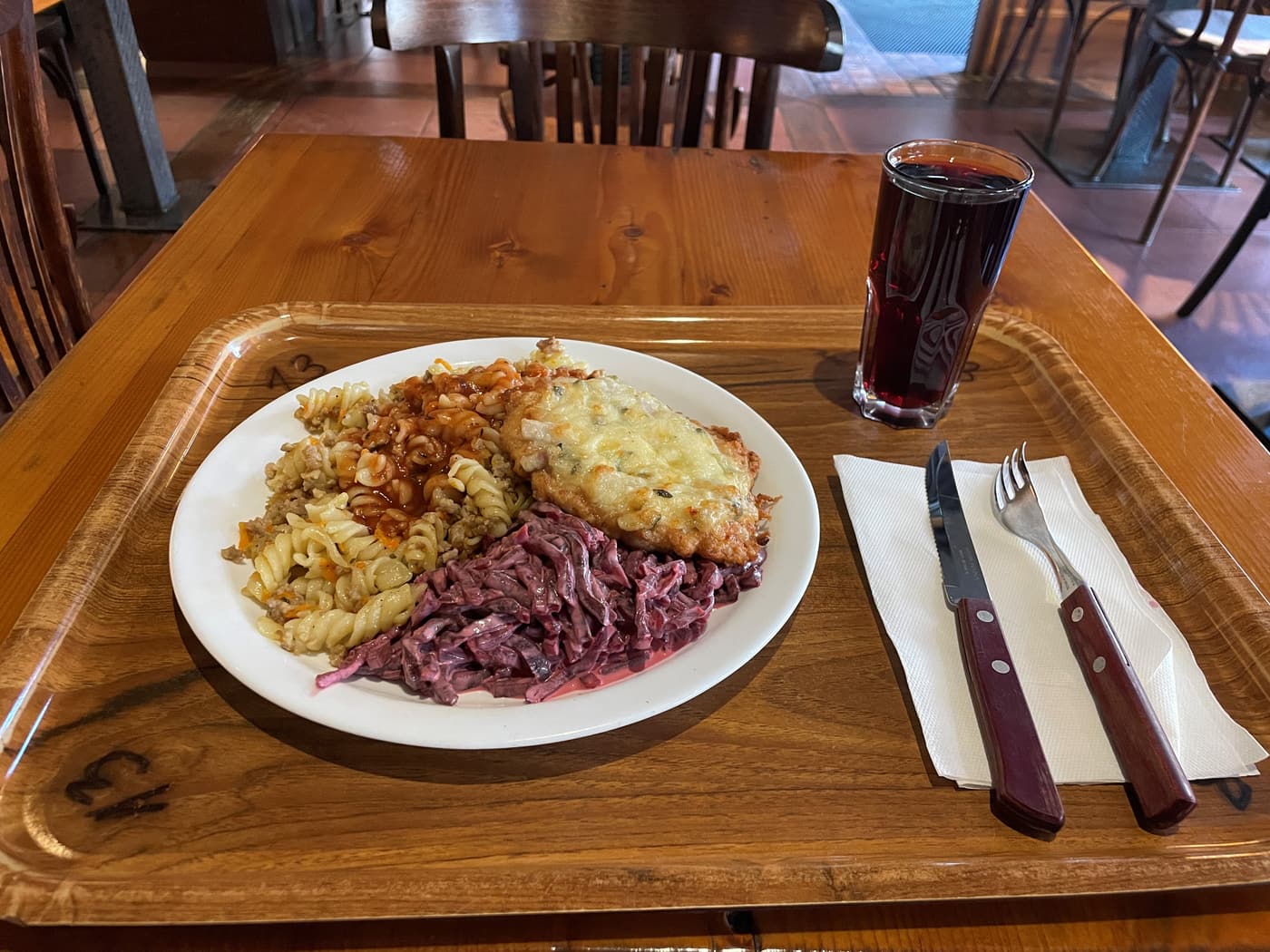 A hearty canteen plate of schnitzel, pasta and creamy red cabbage salad at a Riga eatery