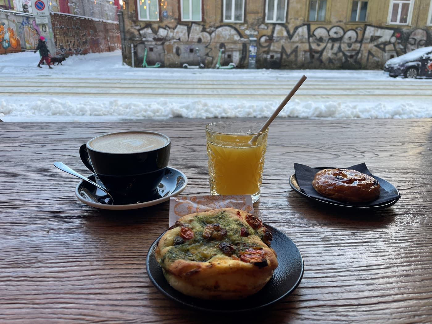 Coffee, fresh orange juice and a savoury tart by the window at MiiT Coffee on a snowy Riga street