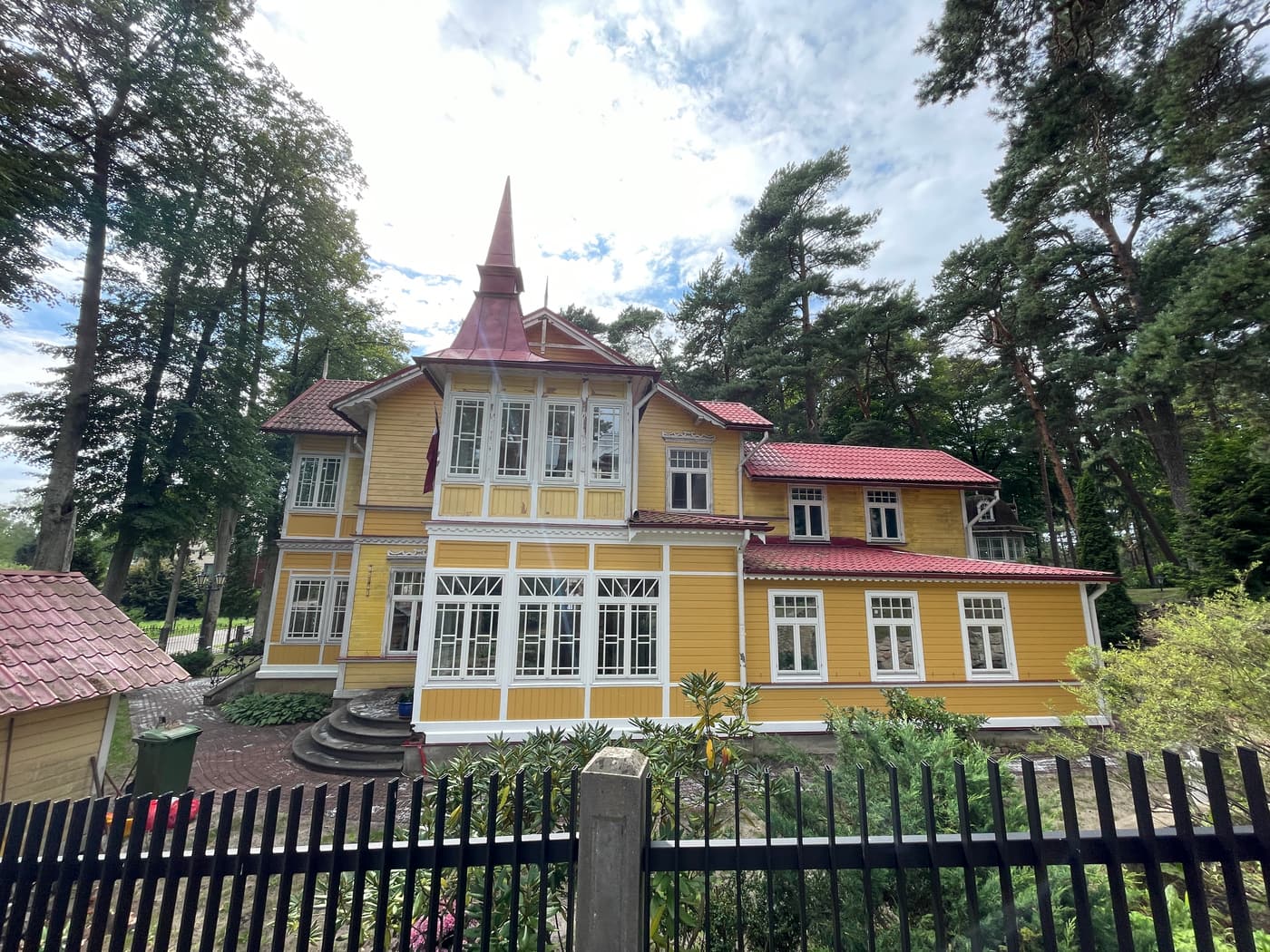 A restored yellow wooden Art Nouveau villa with a turret among the pines in Jūrmala
